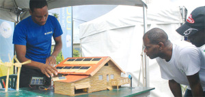 Image of a LUCELEC employee demonstrates to patrons how a solar photovoltaic system works.