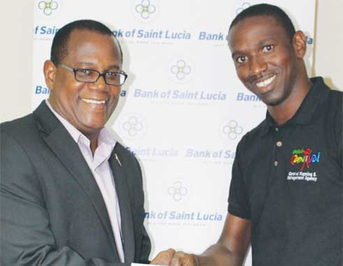 Image of BOSL General Manager HadynGittens which presents the Bank’s sponsorship cheque to Devernant Joseph of the Carnival Planning and Management Agency (CPMA).