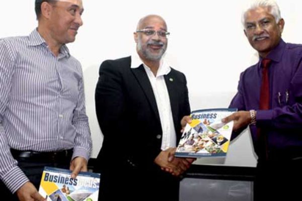AMA's Lokesh Singh (far right) presents copies of the new OECS Business Focus Magazine to Dr. Didacus Jules and Gordon Charles. [Photo: Stan Bishop]