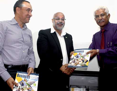 AMA's Lokesh Singh (far right) presents copies of the new OECS Business Focus Magazine to Dr. Didacus Jules and Gordon Charles. [Photo: Stan Bishop]