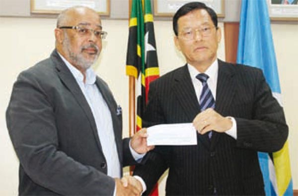 OECS Director-General, Dr. Didacus Jules, receives the cheque on Dominica's behalf from Taiwan's Ambassador to Saint Lucia, James Chang.