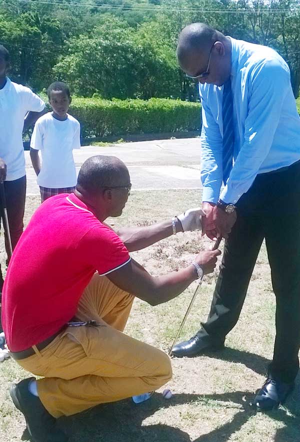 Minister for Youth Development and Sports Shawn Edward takes time out to learn the basics of golf by Pro Golfer Peter David (PhotoL SD)