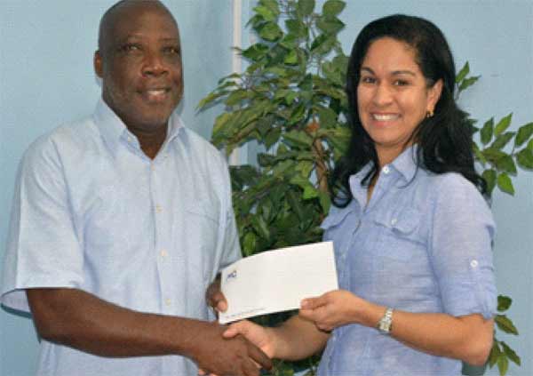 Image: Left to right :Mr. Gregory Piper, Orchestra’s Leader/Conductor, accepting a cheque from Mrs.MarellaDevaux, Group Marketing Manager, M&C Group of Companies.