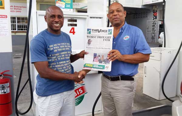 Image: Etienne (right) presents a copy of The VOICE to a customer.