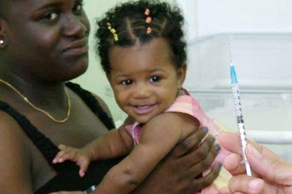 Image: A toddler is about to be vaccinated at the La Clery Health Centre.