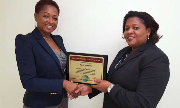 Image: Immediate Past President of the Public Service Toastmasters Club Michelle Charles (left) presents the Distinguished Award to Ms.Monrose
