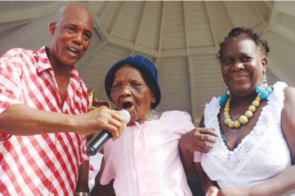Image: Terrence “Cosol” Alexander (left) sharing the microphone with a former La Rose chantwell at last year’s grand fete in Vieux Fort Square.