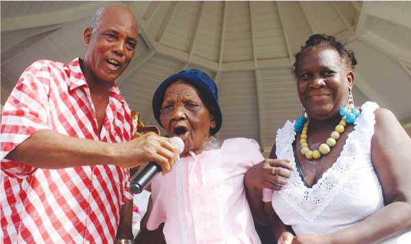 Image: Terrence “Cosol” Alexander (left) sharing the microphone with a former La Rose chantwell at last year’s grand fete in Vieux Fort Square.