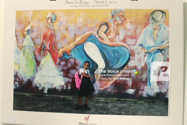 Image: Schoolgirl captured in Maillet-Contoz’s photo of a mural painted by Luigi St. Omer in Anse la Raye. [PHOTO: Stan Bishop]
