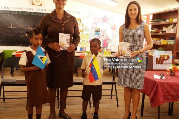 Image: Ambassador Escalona (right) makes the book presentation to school principal Margaret Gabriel and students. (PHOTO: Rochelle Gonzales)