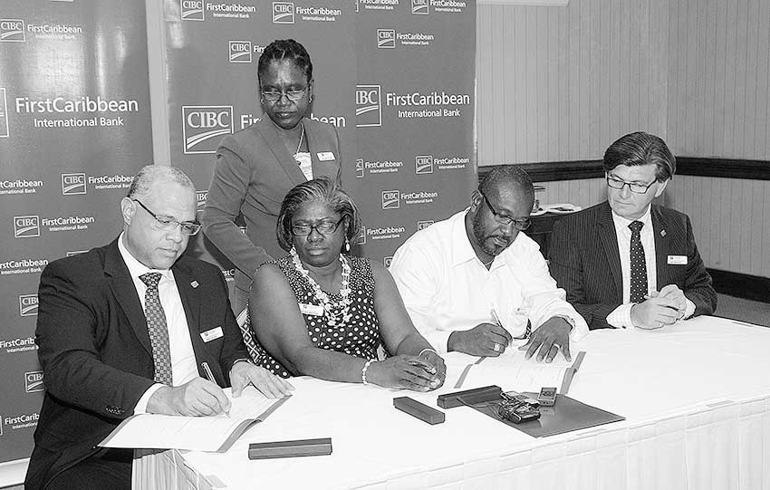 Image: Managing Director, Retail and International Business, CIBC FirstCaribbean, Mark St. Hill (left) signs the agreement while Chairman of the FirstPartnership Teresa Mortimer (second left) observes while Vice-Chairman David Massiah (third left) signs on