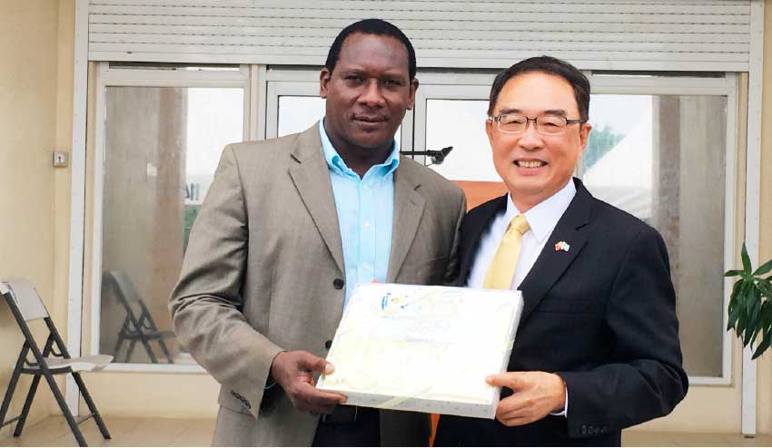 Image: Minister Montoute and Ambassador Shen display one of the items donated by Simplyhelp Foundation. 