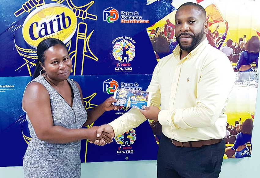 Image of Genifer Madsen (left) receiving her travel package from Carib Beer Brand Manager at PCD, Germaine Serieux.