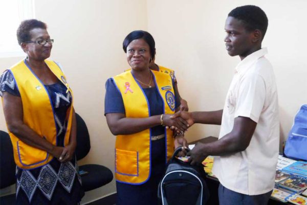 Image of A student of Micoud Secondary School receiving his backpack from a member of the Lions Club of Micoud.
