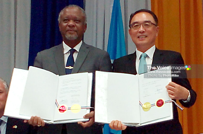 Image of Minister Francis (left) and Ambassador Shen holding up the signed documents. (PHOTO: PhotoMike)