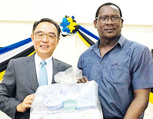Image of His Excellency Ambassador Douglas Shen handover the sample of charity supplies to the Honourable Lenard Montoute
