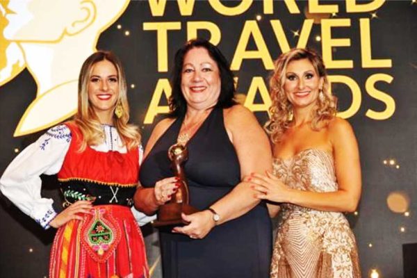 Image of Deana Stefano (centre), Office Manager at Unique Vacations UK Ltd, accepting award on behalf of Sandals Resorts International (SRI).