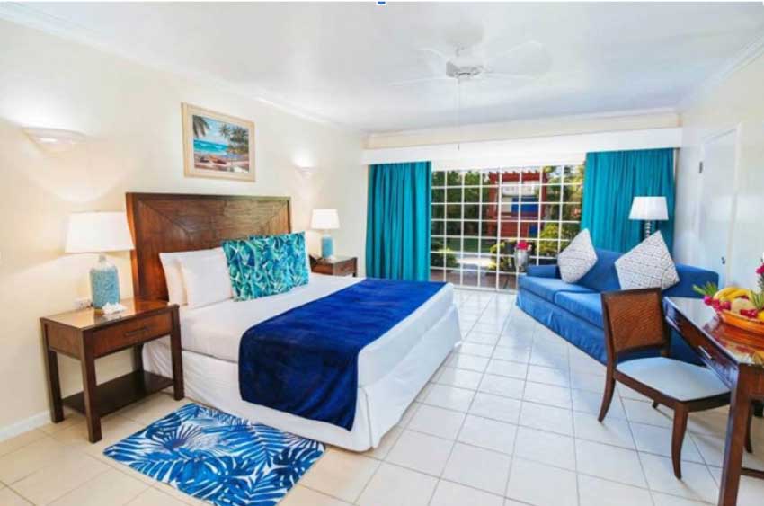 Image: A newly renovated Junior Executive Suite with King bed with Caribbean blue accents. 