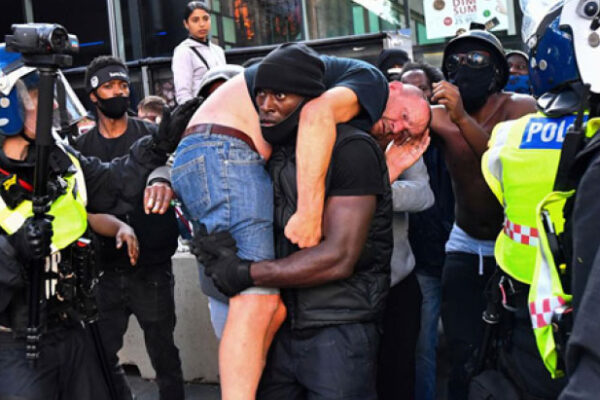 Image of protestor Patrick Hutchinson (centre) carries off an injured white man on his shoulder during a violent scuffle at a protest in London against the murder of George Floyd. Photo Credit: Dylan Martinez/Reuters.