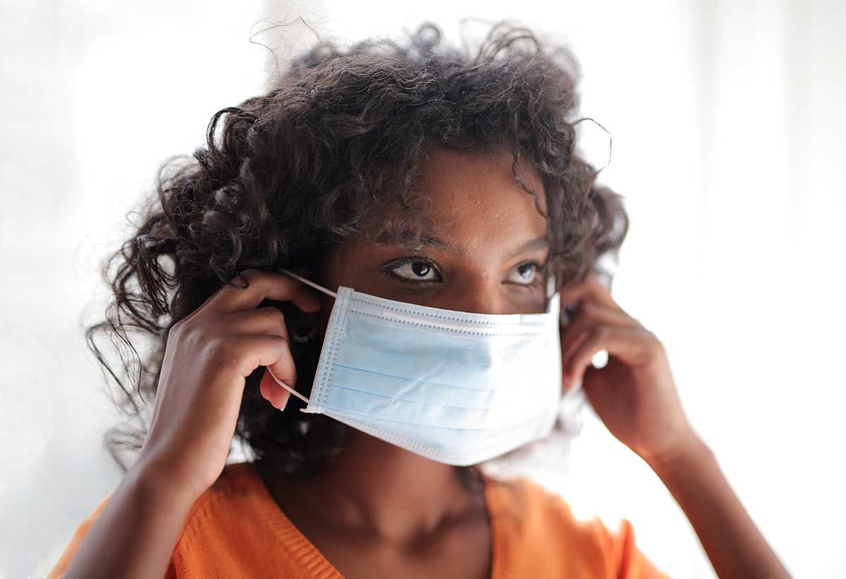Lady putting on a surgical mask to help prevent the spread of COVID-19
