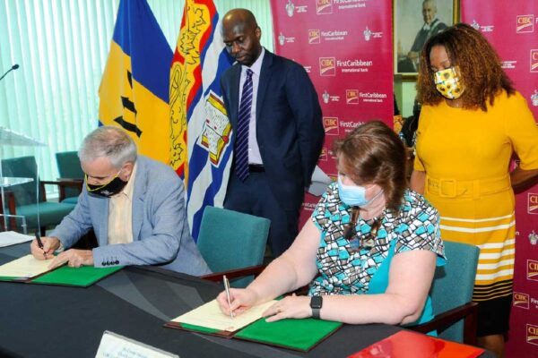 CIBC FirstCaribbean’s Chief Executive Officer Colette Delaney signs a copy of the MOU as does Principal of the Cave Hill campus of the UWI, Professor Clive Landis while the bank’s Director of Corporate Communications Debra King and Deputy Principal of Cave Hill campus Professor Winston Moore observe.