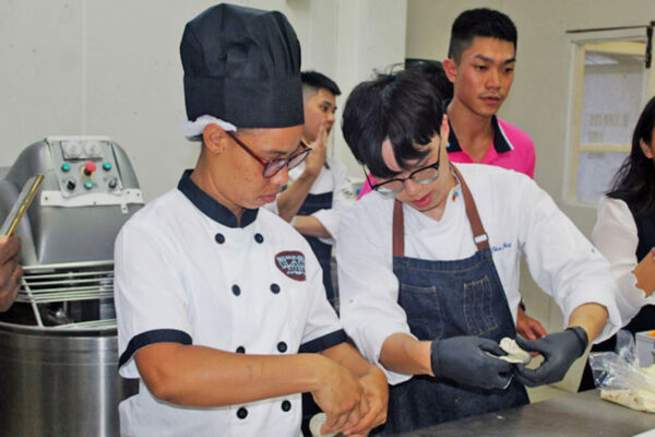 Chef Louis Hsieh, a Taiwan Youth Ambassador, right, demonstrates to a local baker how to fold a bagel during the bakery workshop at Glace Bakery on Wednesday, September 6.