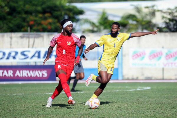 A Guadeloupian striker (red outfit) takes on Team Saint Lucia’s defense