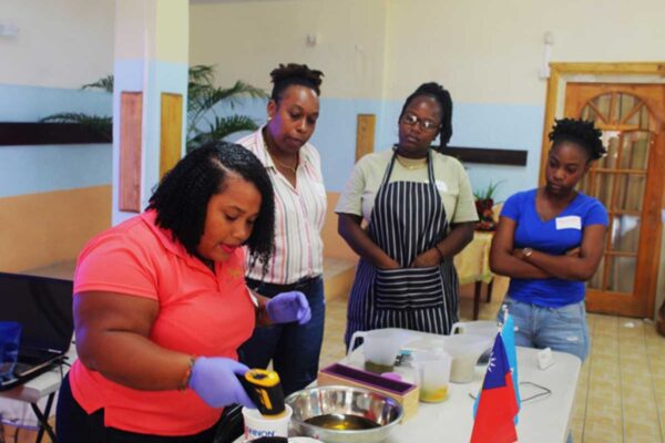 Facilitator Kishma Louis (far left )demonstrating to participants how to mix ingredients in the soap-making process.