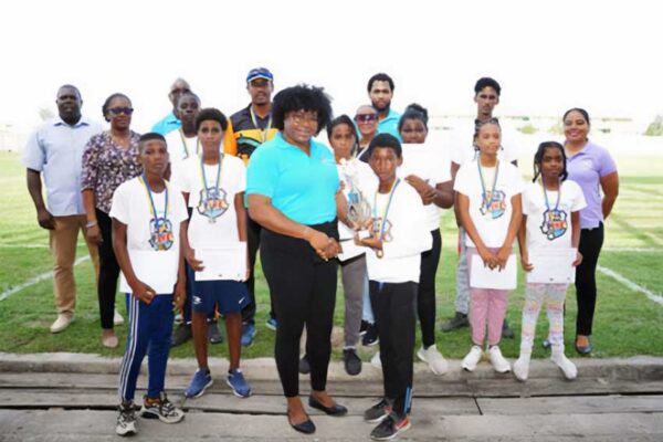 Zaleel Thomas of River Doree Anglican Combined School receives trophy from Florence Demacque, RBEC Vieux Fort- Branch Manager, also in the photo, Director of Sports Clivus Jules, Principal Secretary of the SLNCA Jacqueline Inglis and coaches from Zone 5