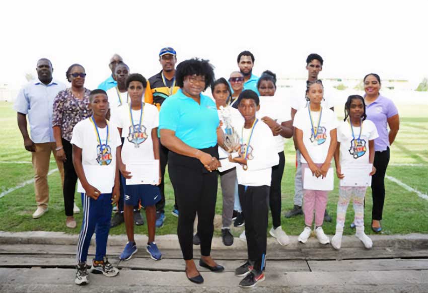 Zaleel Thomas of River Doree Anglican Combined School receives trophy from Florence Demacque, RBEC Vieux Fort- Branch Manager, also in the photo, Director of Sports Clivus Jules, Principal Secretary of the SLNCA Jacqueline Inglis and coaches from Zone 5 