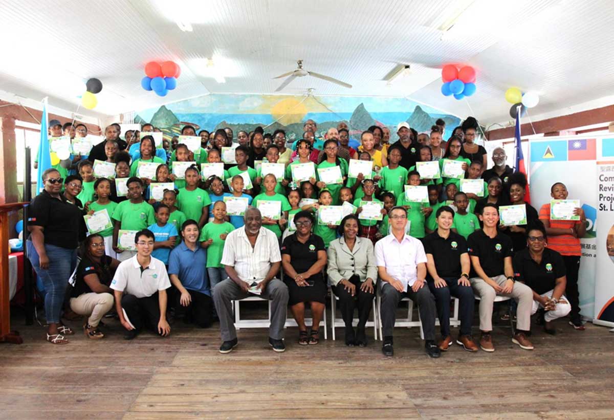 H.E. Peter Chia-Yen Chen, Taiwan’s Ambassador to Saint Lucia, joins Hon. Emma Hippolyte, Parliamentary Representative for Soufriere/Fond St. Jacques; Mrs. Sandra Prospere, President of the Fond St. Jacques Development Committee, camp participants and others pose for a group photo.