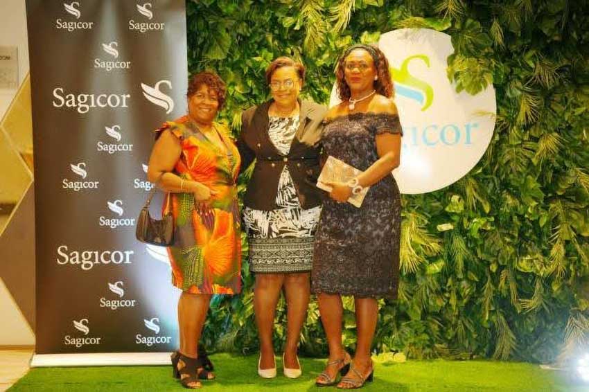 General Manager Sagicor Life (Eastern Caribbean) Inc., Carol Mangal takes a moment to take a photo with colleagues in front of the Sagicor sign